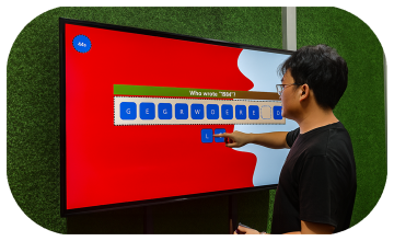 Guest playing word scramble game on large touchscreen at Dubai event with branded graphics and green artificial grass wall background.